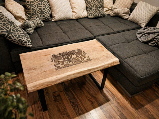 Holztisch mit kunstvollem Design, auf einem gemütlichen, grauen Sofa mit Kissen.