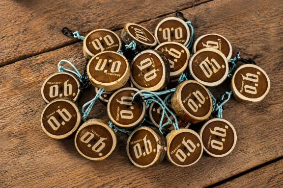 Eine Ansammlung von Holzanhängern mit eingravierten Buchstaben und blauen Schnüren.