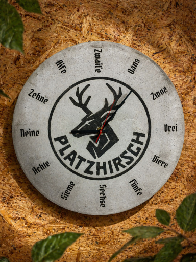 Runde Plakette mit dem Schriftzug „Platzhirsch“ und einem Hirschkopf in der Mitte.