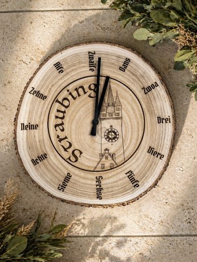 Holzuhren-Design mit römischen Ziffern und schwarzem Zifferblatt auf einem Holzscheit.