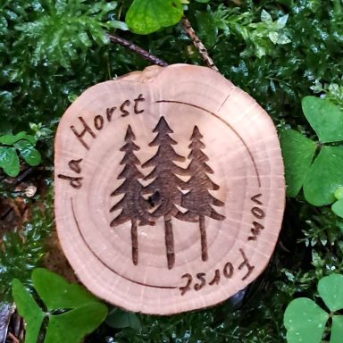 Holzscheibe mit eingravierten Tannenbäumen und dem Schriftzug "da Horst vom Forst".