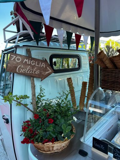 Dolcina Ein Verkaufsstand mit einer Holztafel, Pflanzen und Dekoration in bunten Farben.
